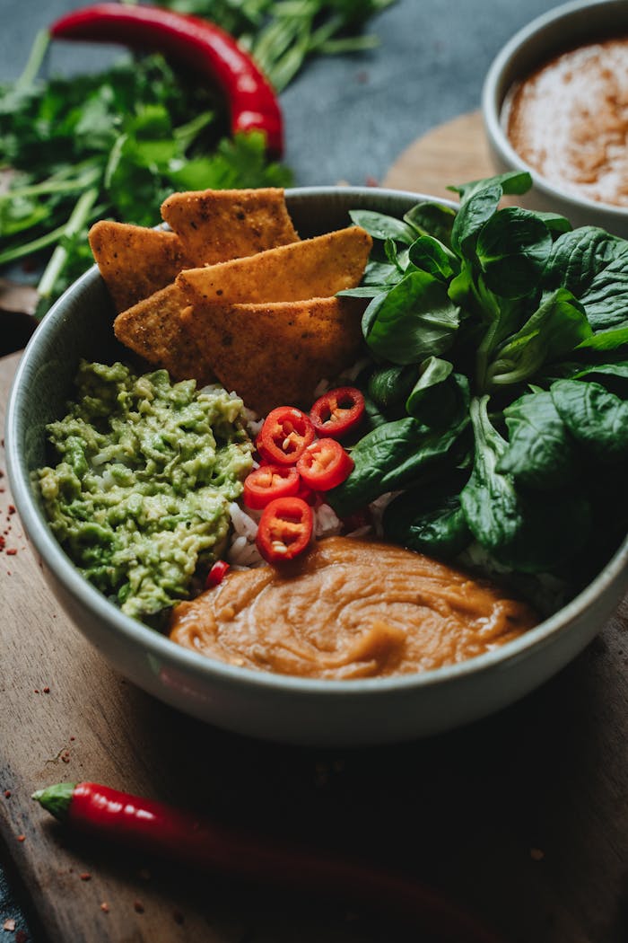 A delicious vegan rice bowl topped with guacamole, chili peppers, and fresh greens.